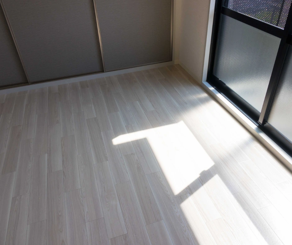 Light wood-look laminate floor in a sunlit room beside a large window