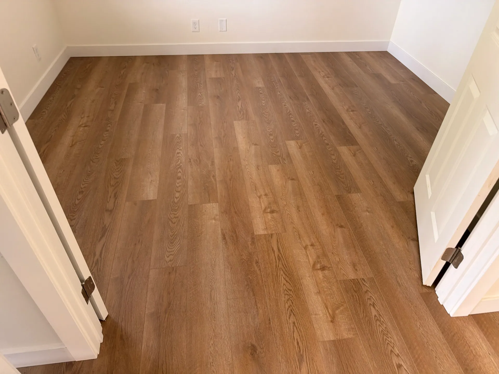 Wood-look plank flooring installed wall to wall in an Oklahoma City bedroom, seen from the doorway